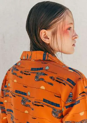 Model in profile, seen from behind, in an orange shirt with a navy and grey print
